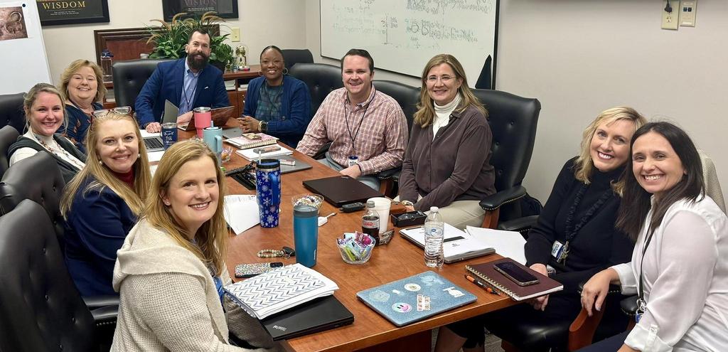 10 adults sitting around a conference table smiling