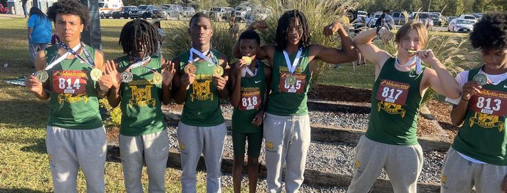 Seven athletes pose with medals, displaying their numbers in a park setting.