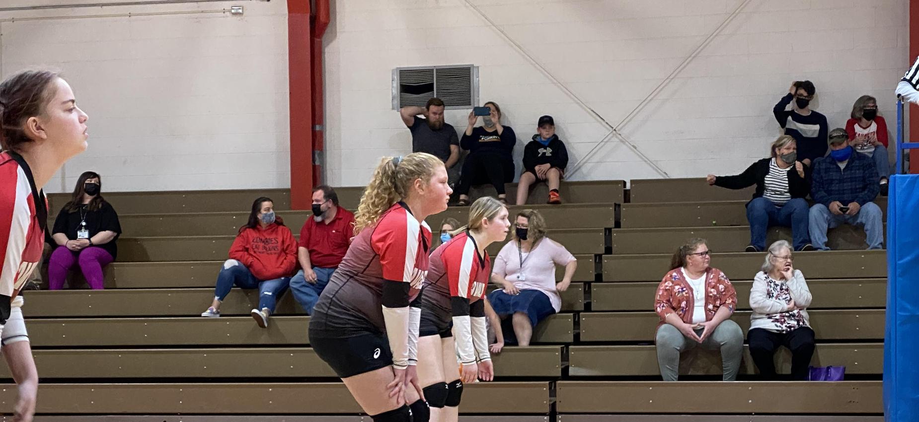 Two volleyball players wait for a serve.