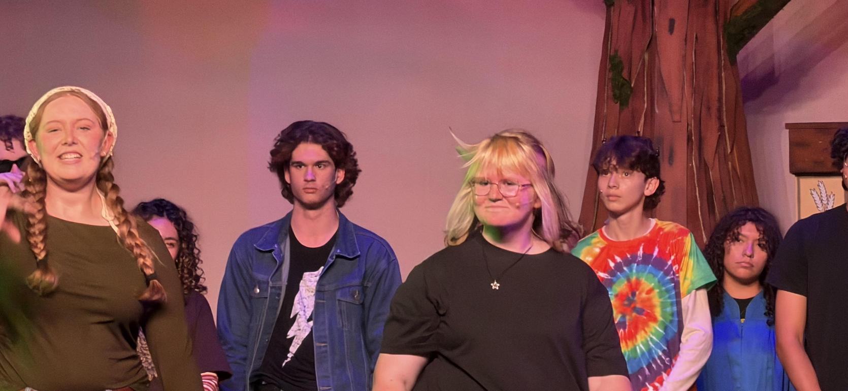 A group of young performers standing on stage during a theatrical performance.