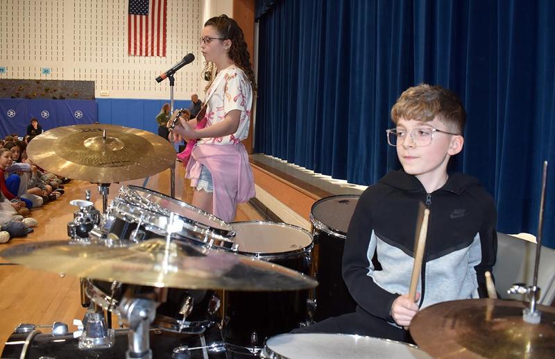 a girl playing guitar and a boy playing the drums