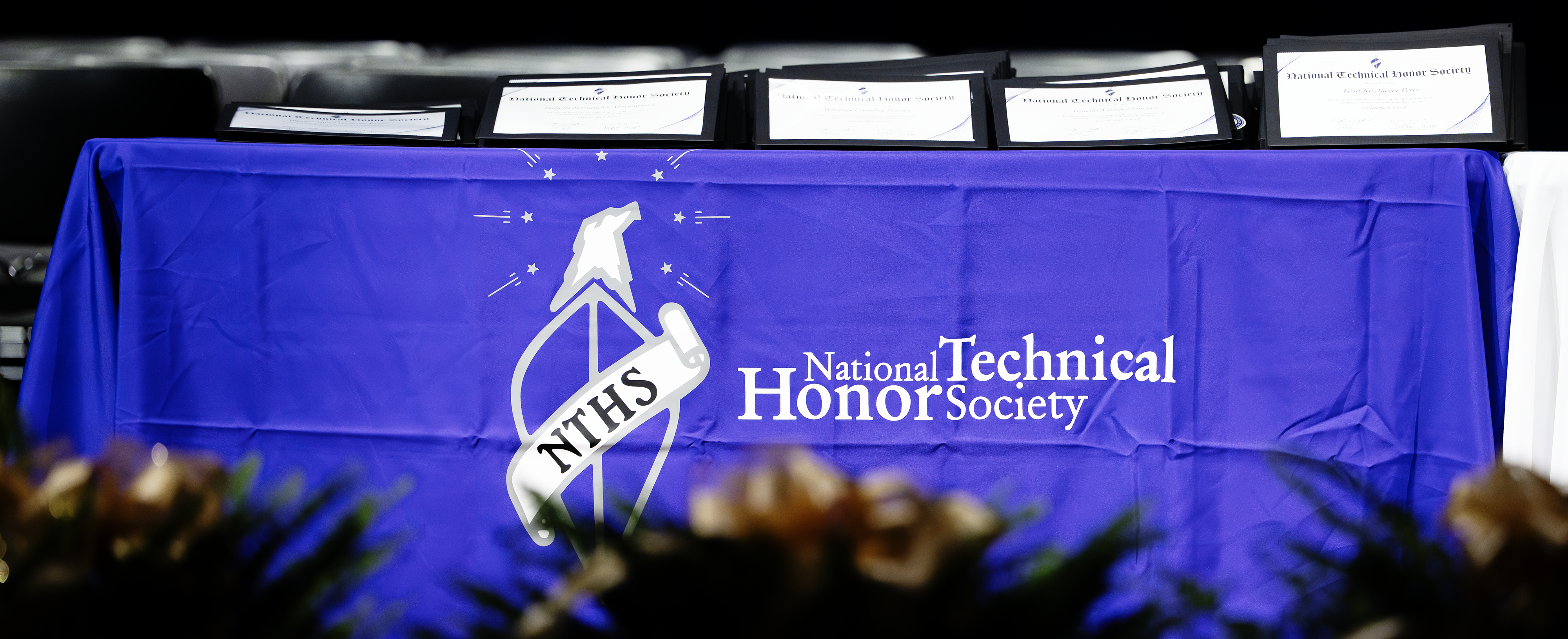 A table with a blue cloth displaying certificates and a National Technical Honor Society logo.