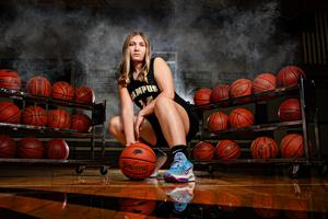 Woods posing with racks of basket balls in gym 2026