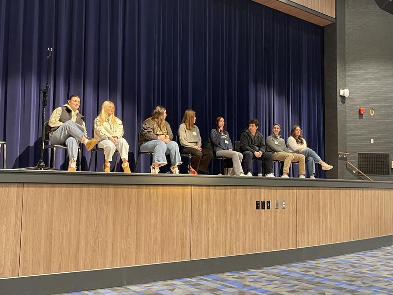recent high school graduates seated on stage with microphone