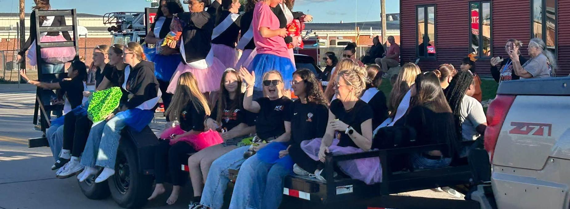 Group of young women in colorful outfits enjoying a parade on a float.