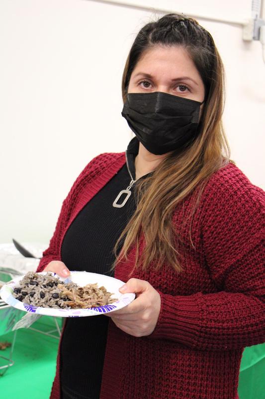 Woman wearing mask and holding plate of food looking at camera