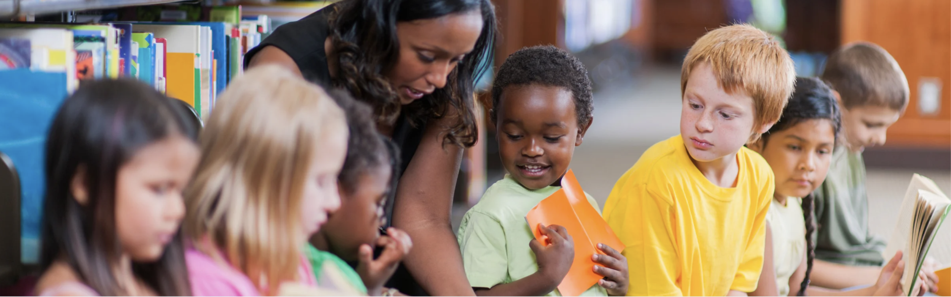 A teacher holds a book with a group of young students