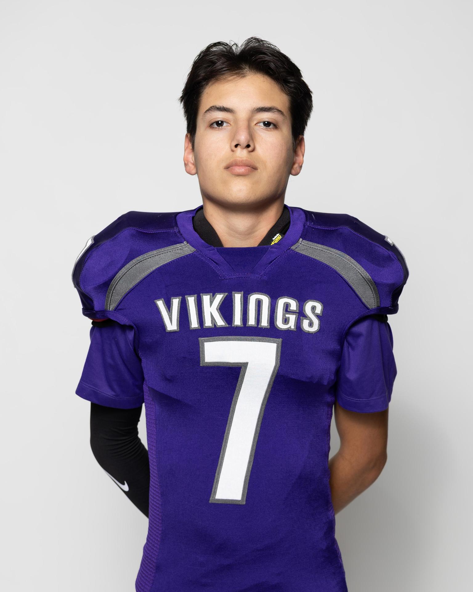 Athlete in a purple football uniform with the number 7, standing confidently.