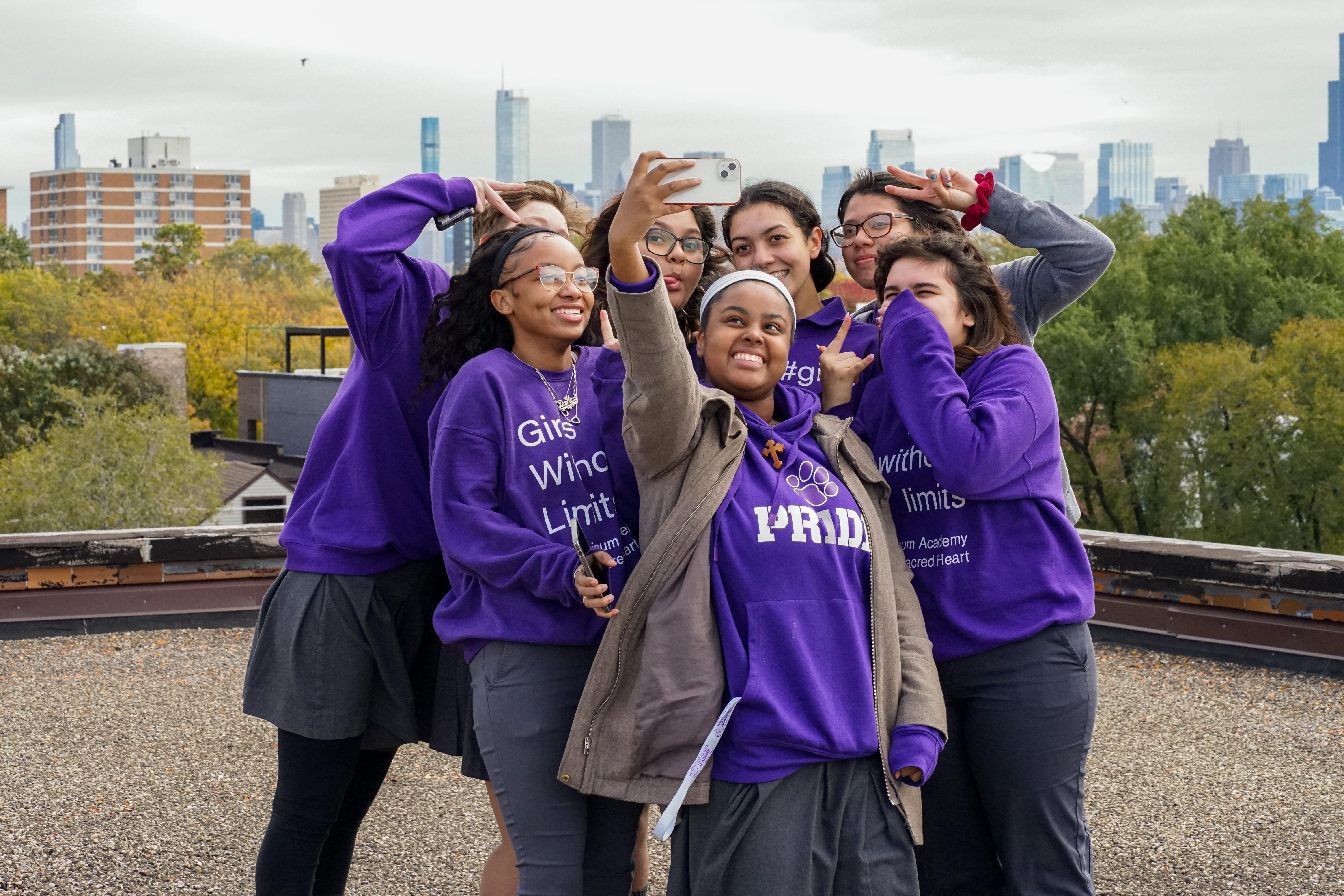 Students posing for a selfie on the rooftop with Chicago skyline in background