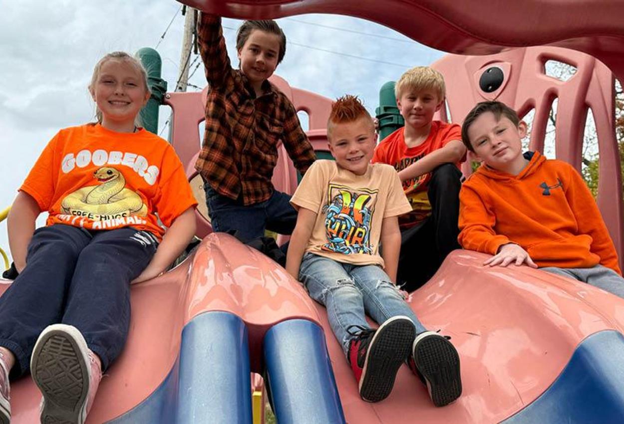 Harrison Park student sit on the sliding board while dressed in orange for Red Ribbon spirit week