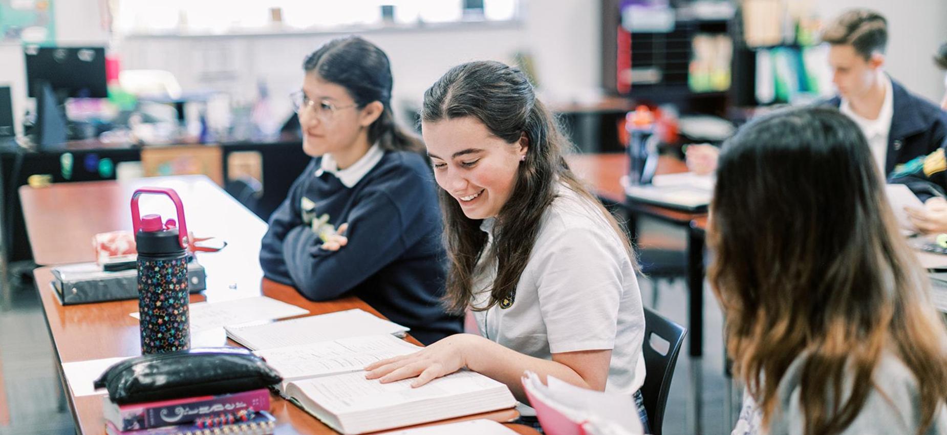 High school students talk and work together at a classroom table