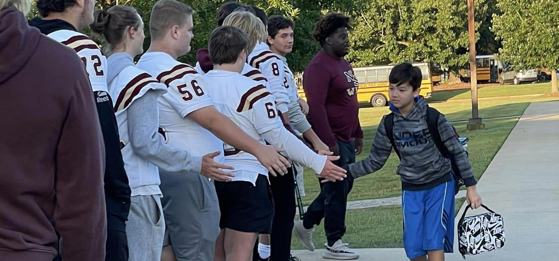 Football players greeting student