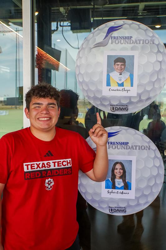 Student points to his photo on the large golf balls hanging on the wall