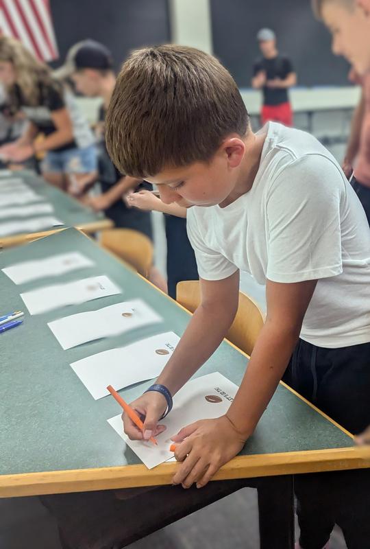 A student signs a thank you card.