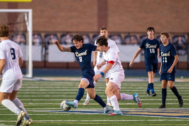 soccer playing kicking ball with opponent beside him