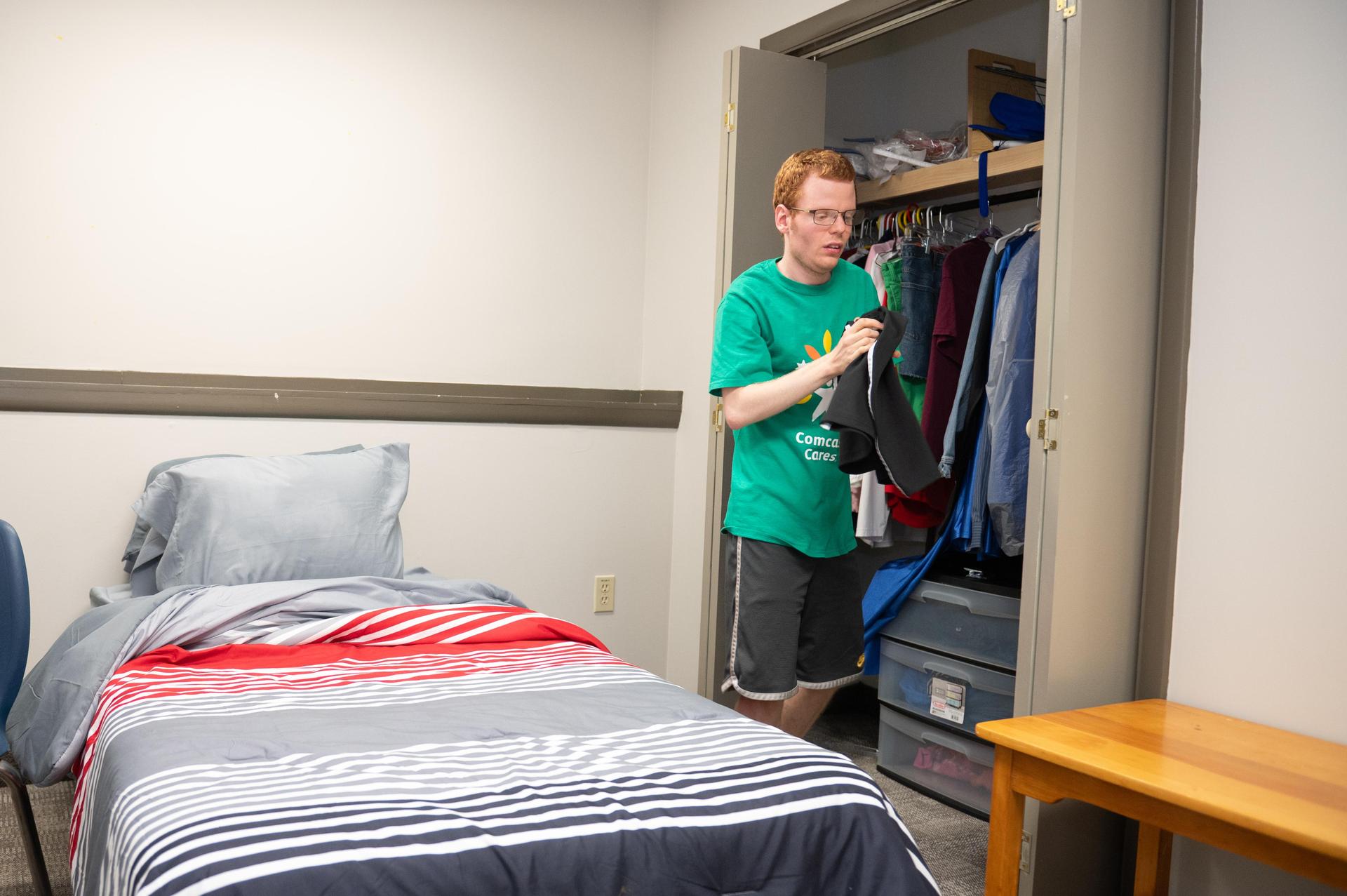 Student in green shirt hanging up clothes.