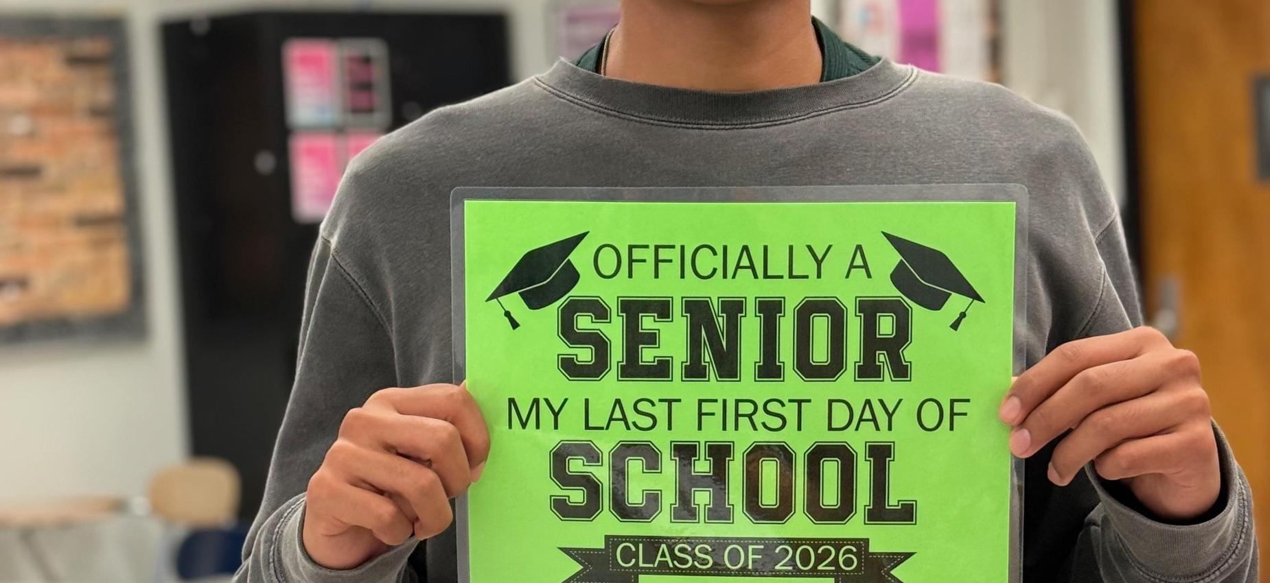 A students holding an "Officially a senior. My last day of school" sign