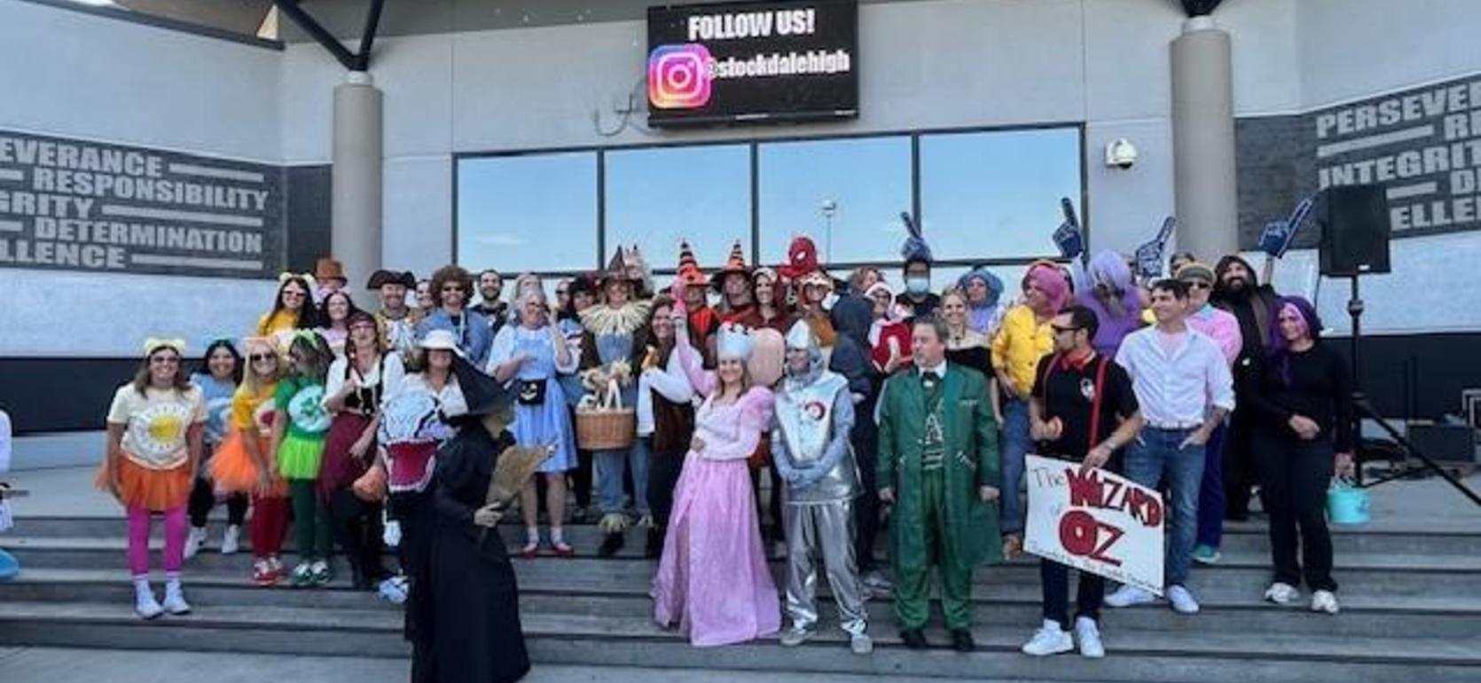 A large group of people dressed in colorful costumes gathered on steps for a photo.