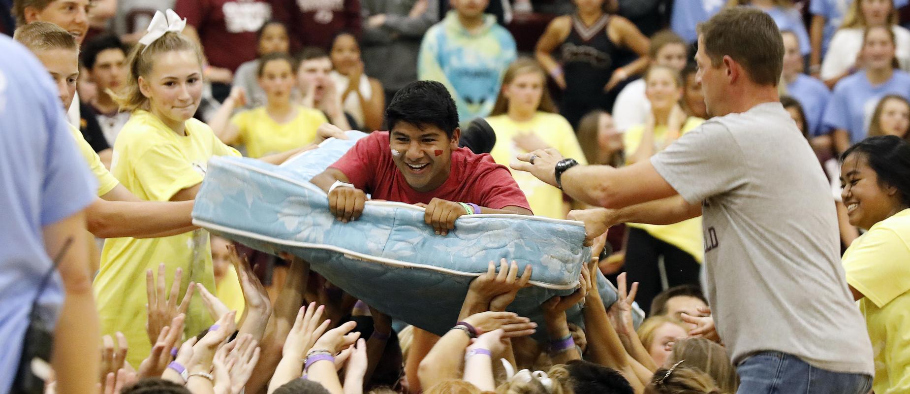 boy in mattress relay floats across gym with help of classmates