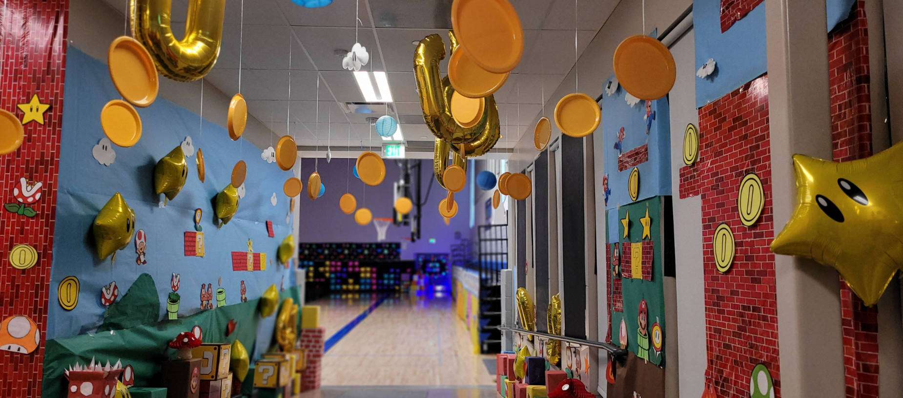 A decorated hallway with balloons, coins, and colorful wall designs inspired by games.