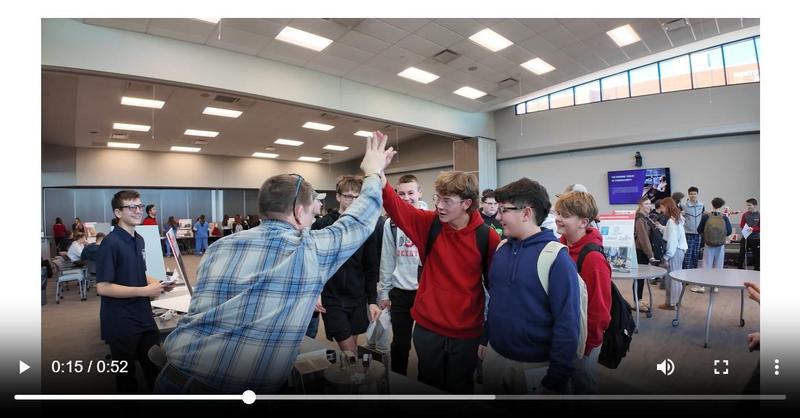 This is a thumbnail image from the attached video that captures a student high fiving an instructor