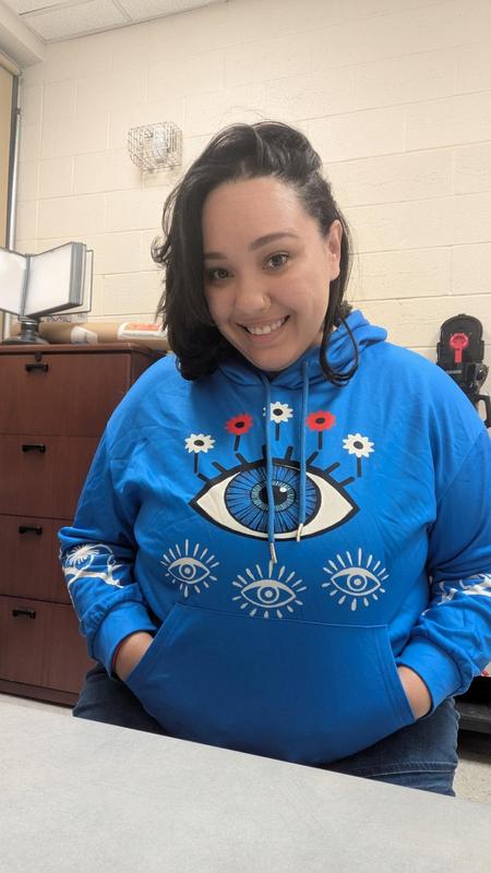 Ms. Aquino sitting at her desk in a blue hoodie