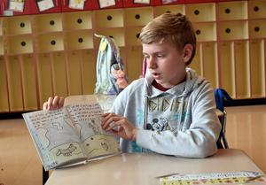 Child showing illustrations in a book while seated at a desk.
