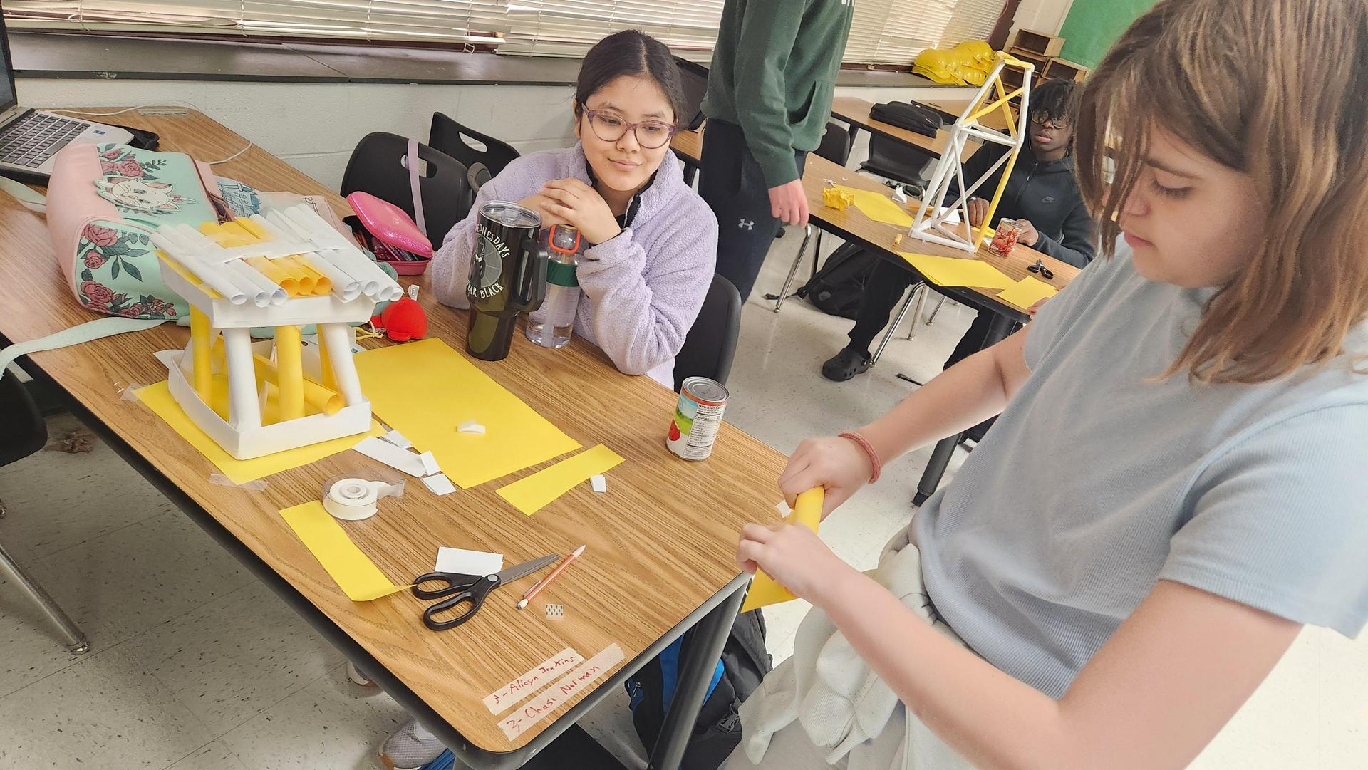 Students working on a school project with materials on a table.