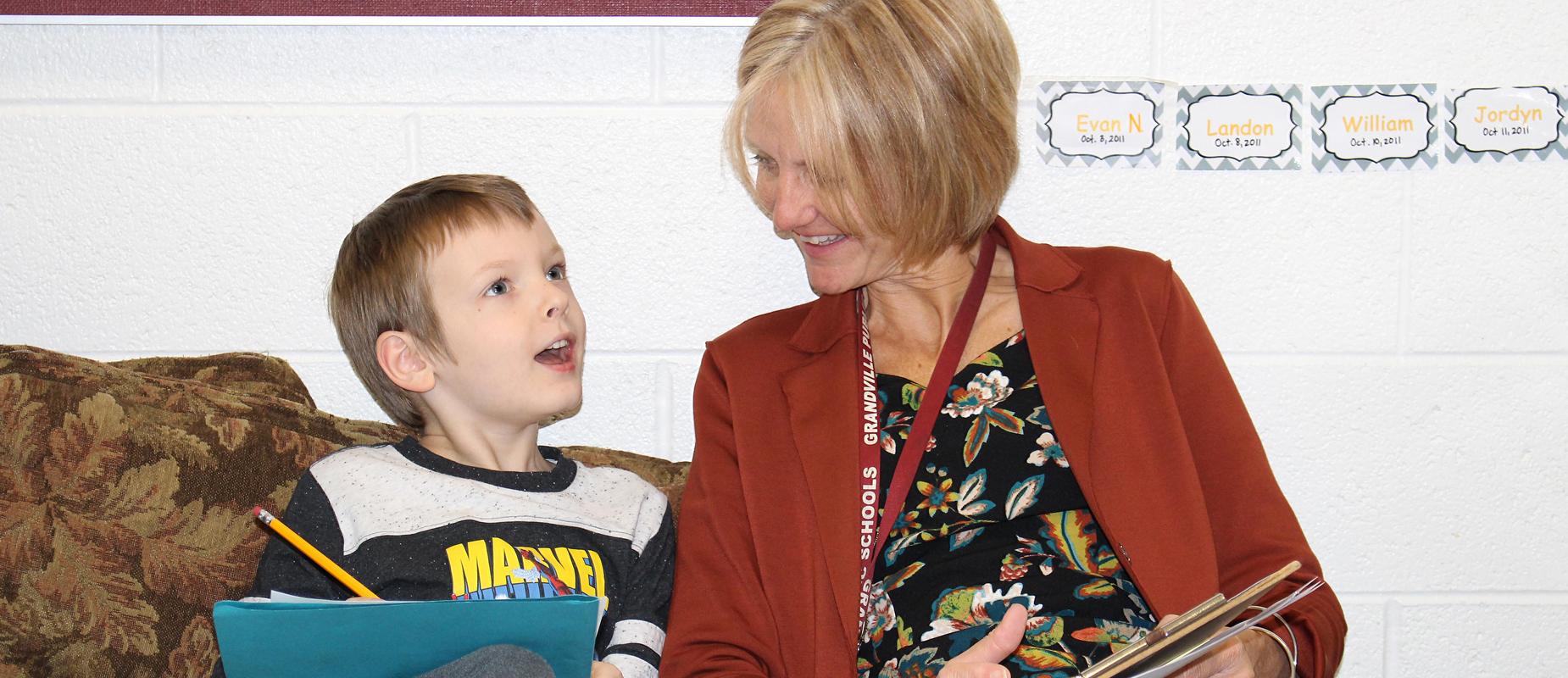 boy with pencil and folder talks to teacher with folder and pen