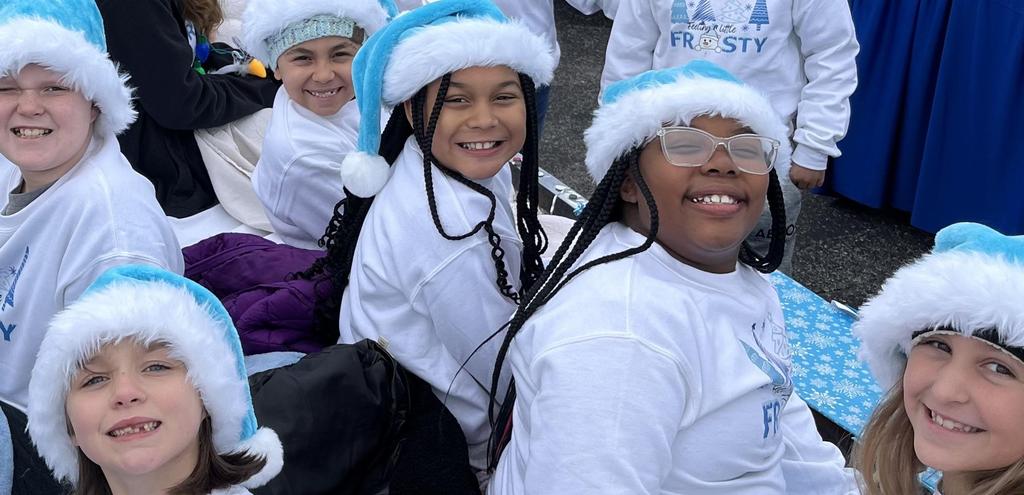 kids sitting on parade float in matching shirts and hats