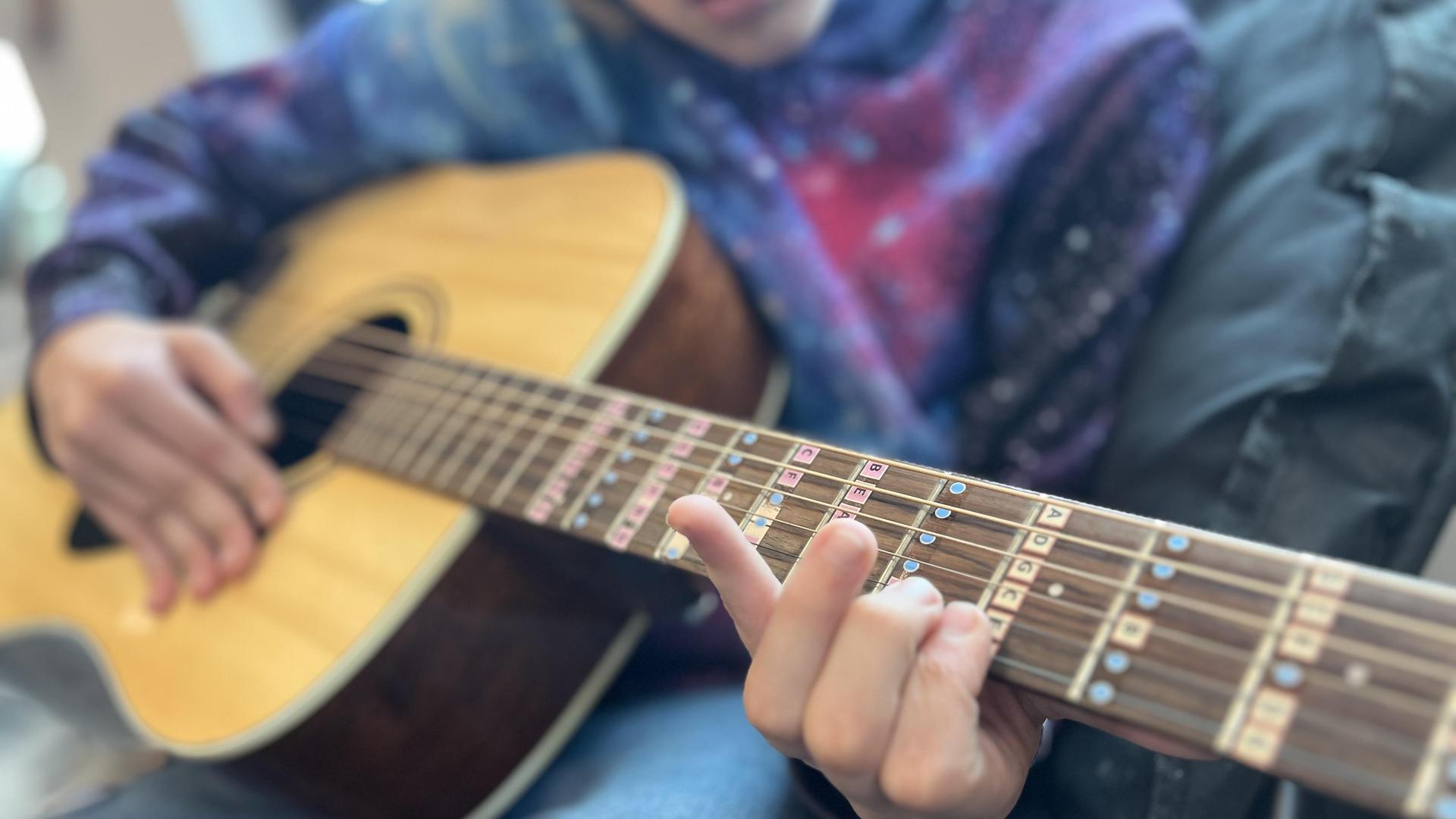 Close up of a student playing a guitar