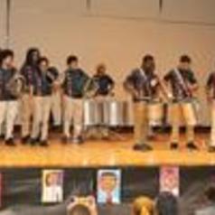 A group of drummers performing on stage in matching outfits.