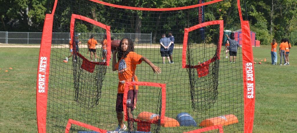 girl throws football into a net