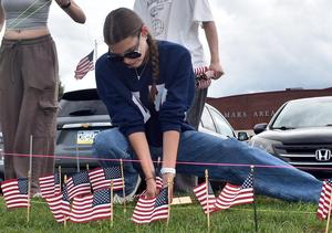 A person sits, positioning several small American flags in a row.