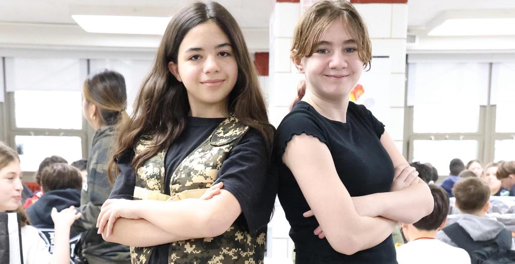 Two girls with arms crossed standing back to back.