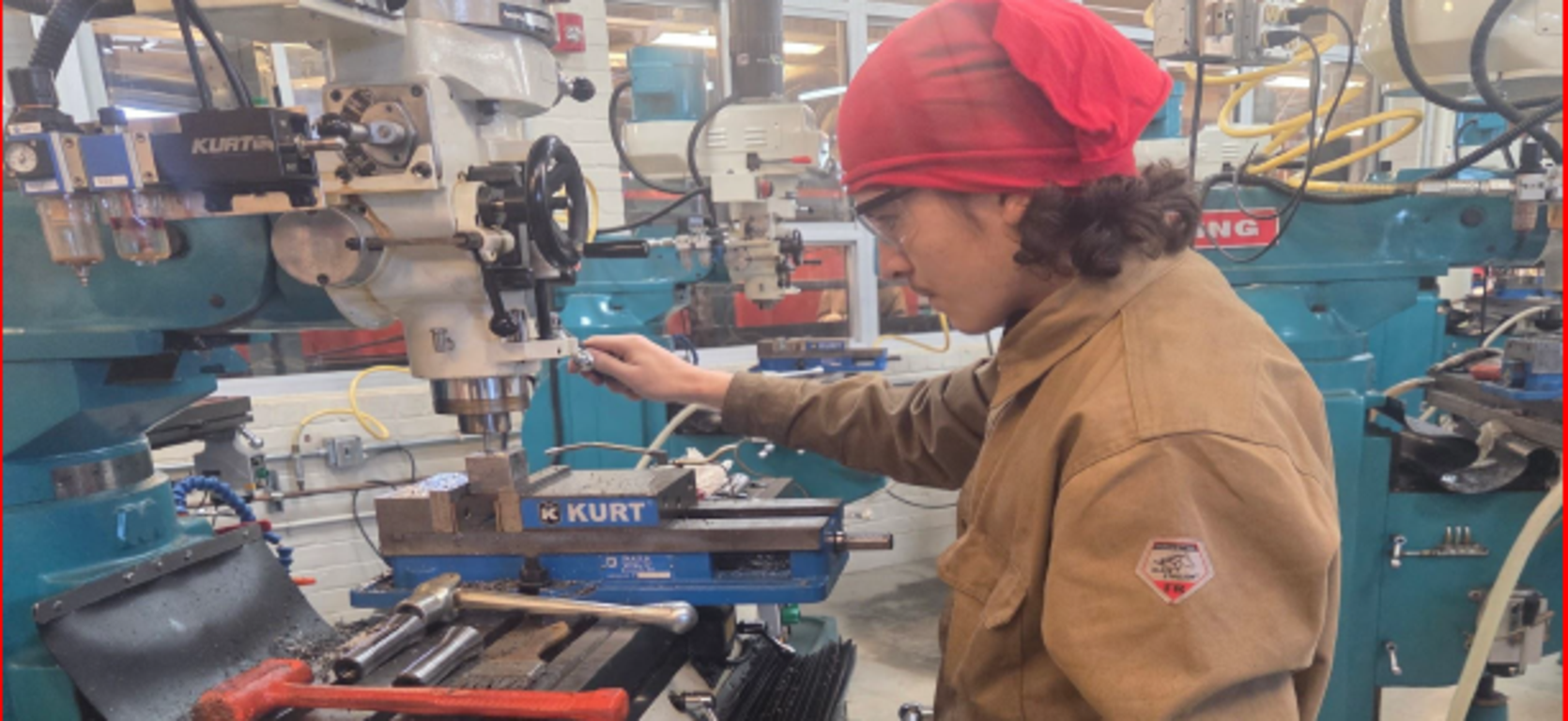 A person operating a milling machine in a workshop.