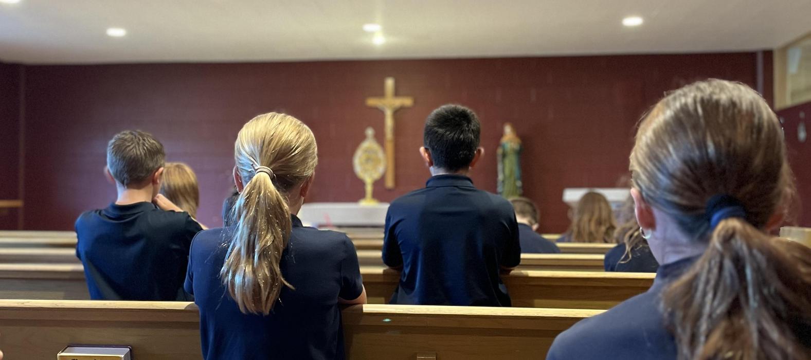 Children sitting in pews during a religious ceremony.