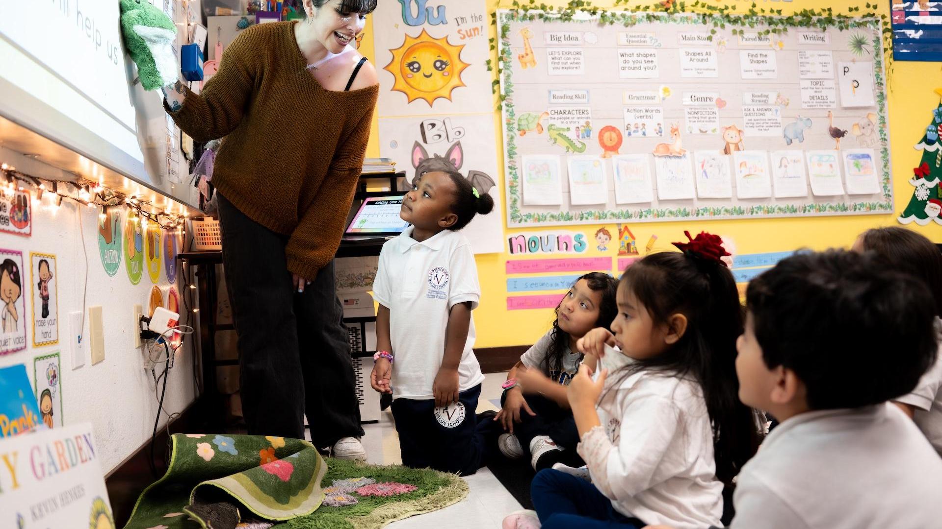 A teacher interacting with young students during a lesson in a classroom.