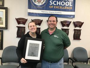 Suzanne Shearer holds her Harmony Magnet Academy Certificated Teacher of the Year award plaque while posing with a colleague.