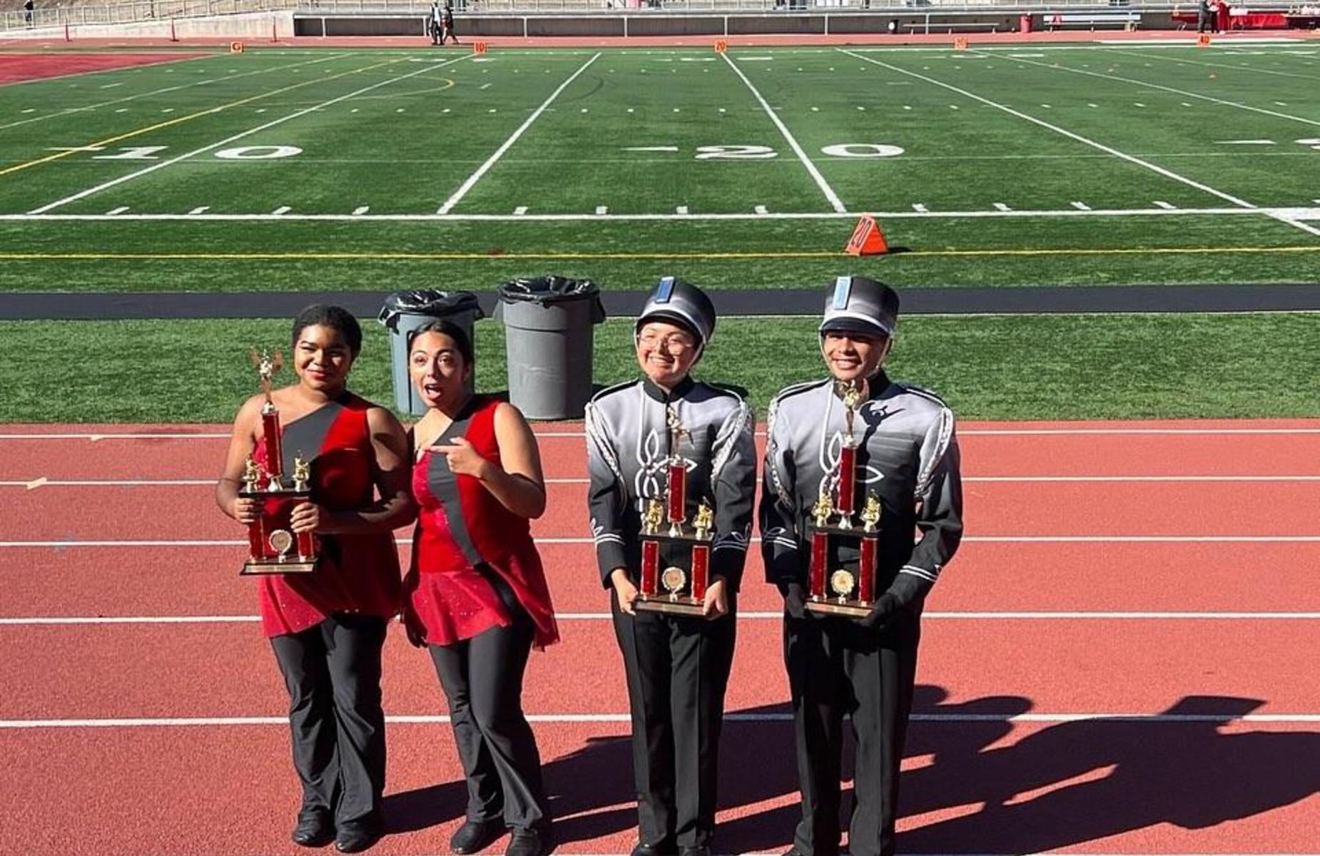 four students hold up trophies won at parade