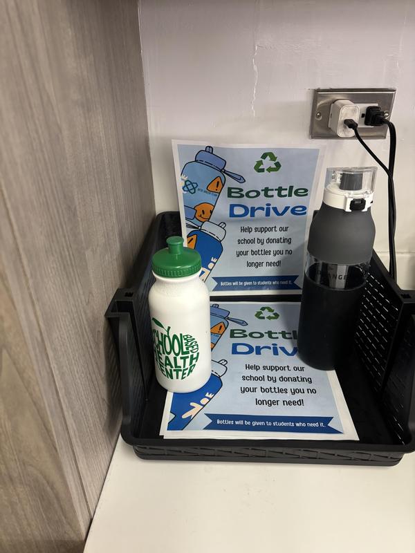 Tray with bottles and a sign promoting a school bottle drive for donations.