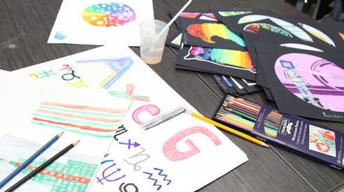 Colorful art supplies and drawings spread out on a table.