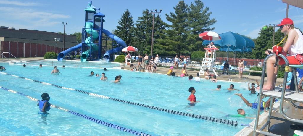 students play in the pool while others sit on the side, feet in water