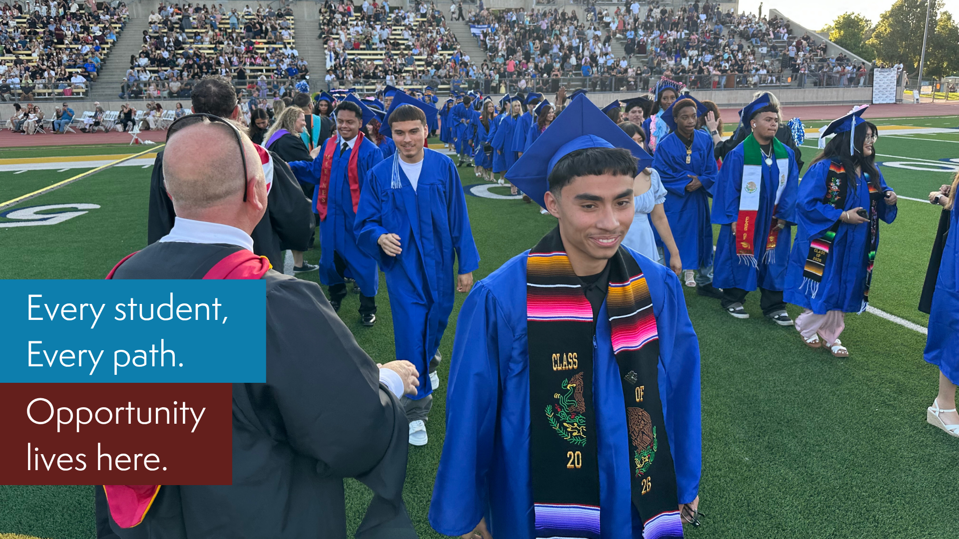 Students in blue gowns processing during a graduation event.