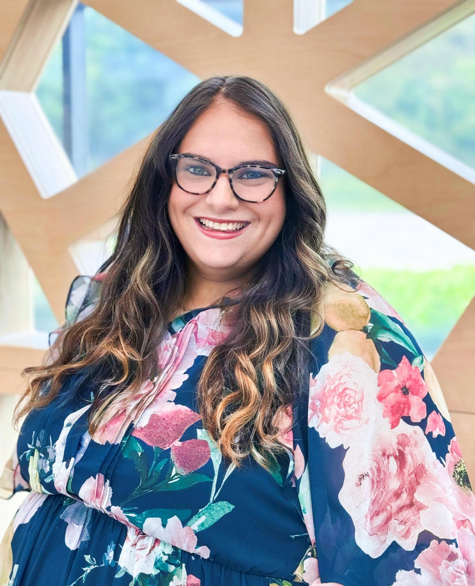 Katie Foster wearing floral dress and glasses, woman smiling