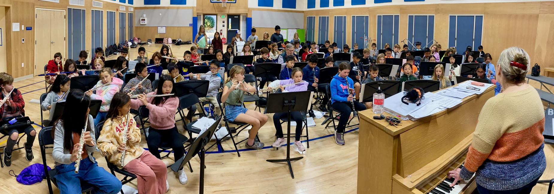 Lincoln students in a music class playing flutes with a teacher at a piano.