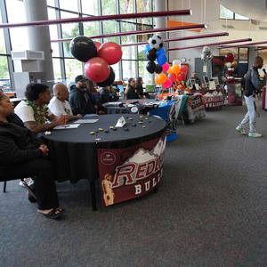 Athletes at tables in front of the room, waiting to sign commitment letters