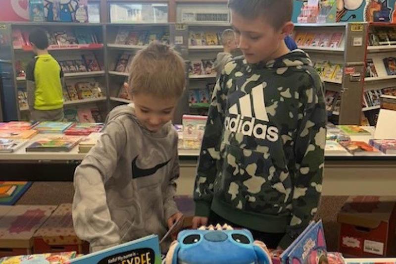 A kindergartener and a 5th-grader look at the book selection together