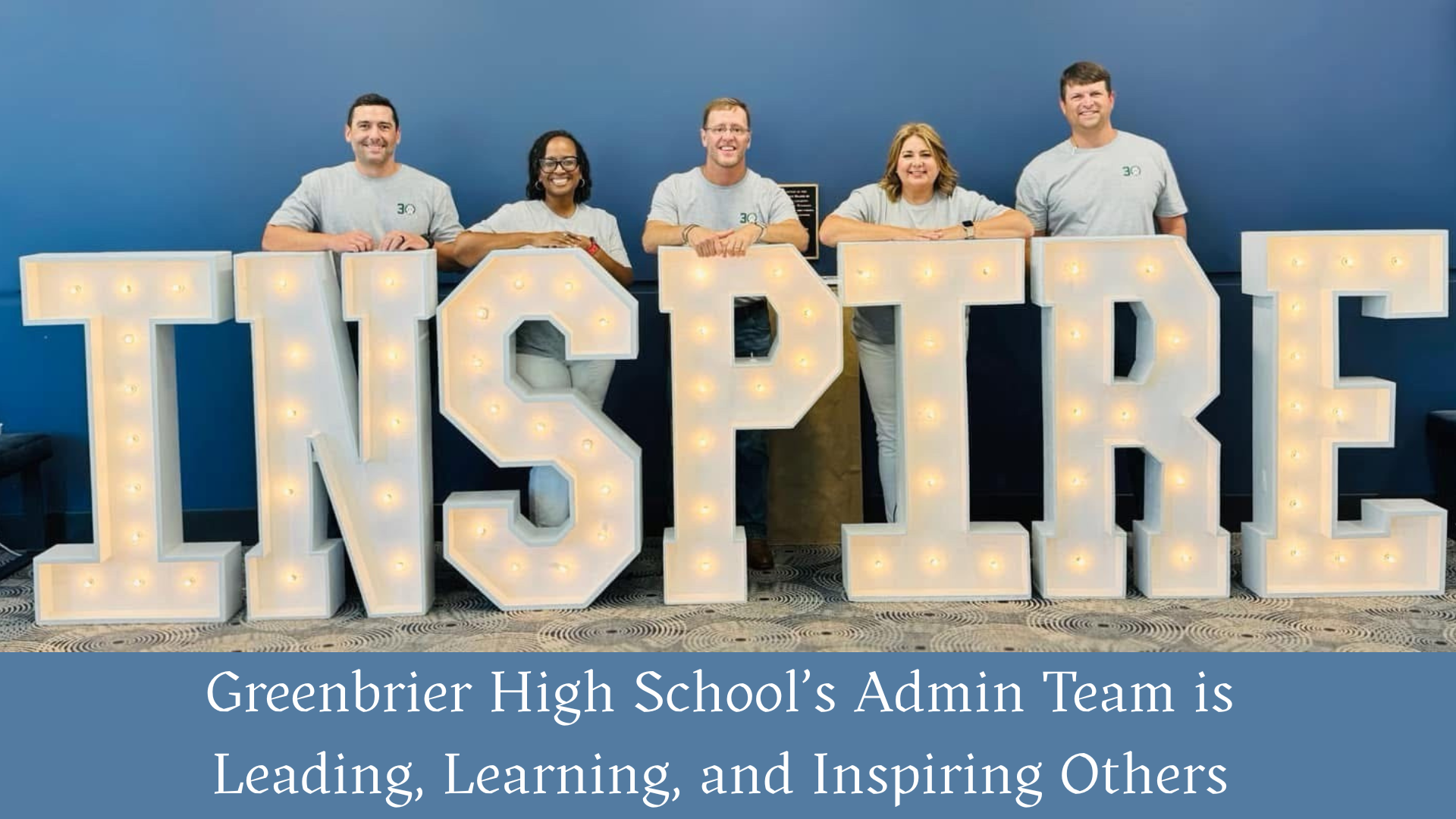 Six members of Greenbrier High School's Admin Team standing behind large illuminated letters spelling 'INSPIRE'.