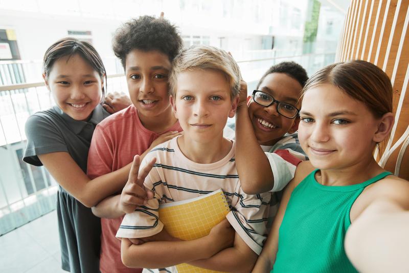 Five middle school friends take a selfie together inside a school